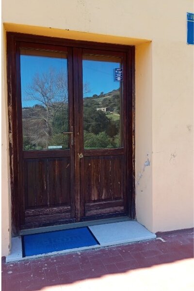 Wooden door with reflective glass and blue doormat outside