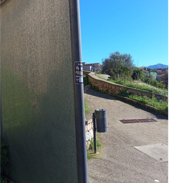 Pedestrian path with stone wall and trash bin under clear blue sky