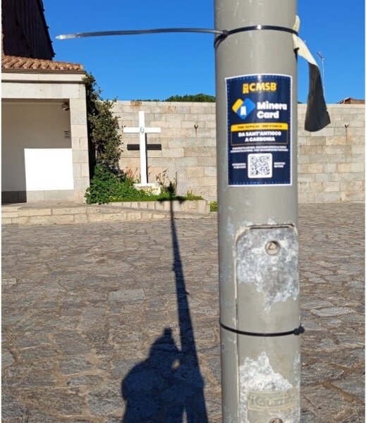 Cartello Minera Card su palo con ombra di croce su pavimento in pietra