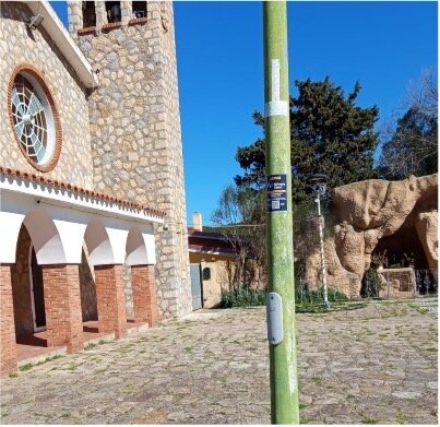 Vista di una chiesa in pietra con arco e campanile sotto un cielo azzurro.