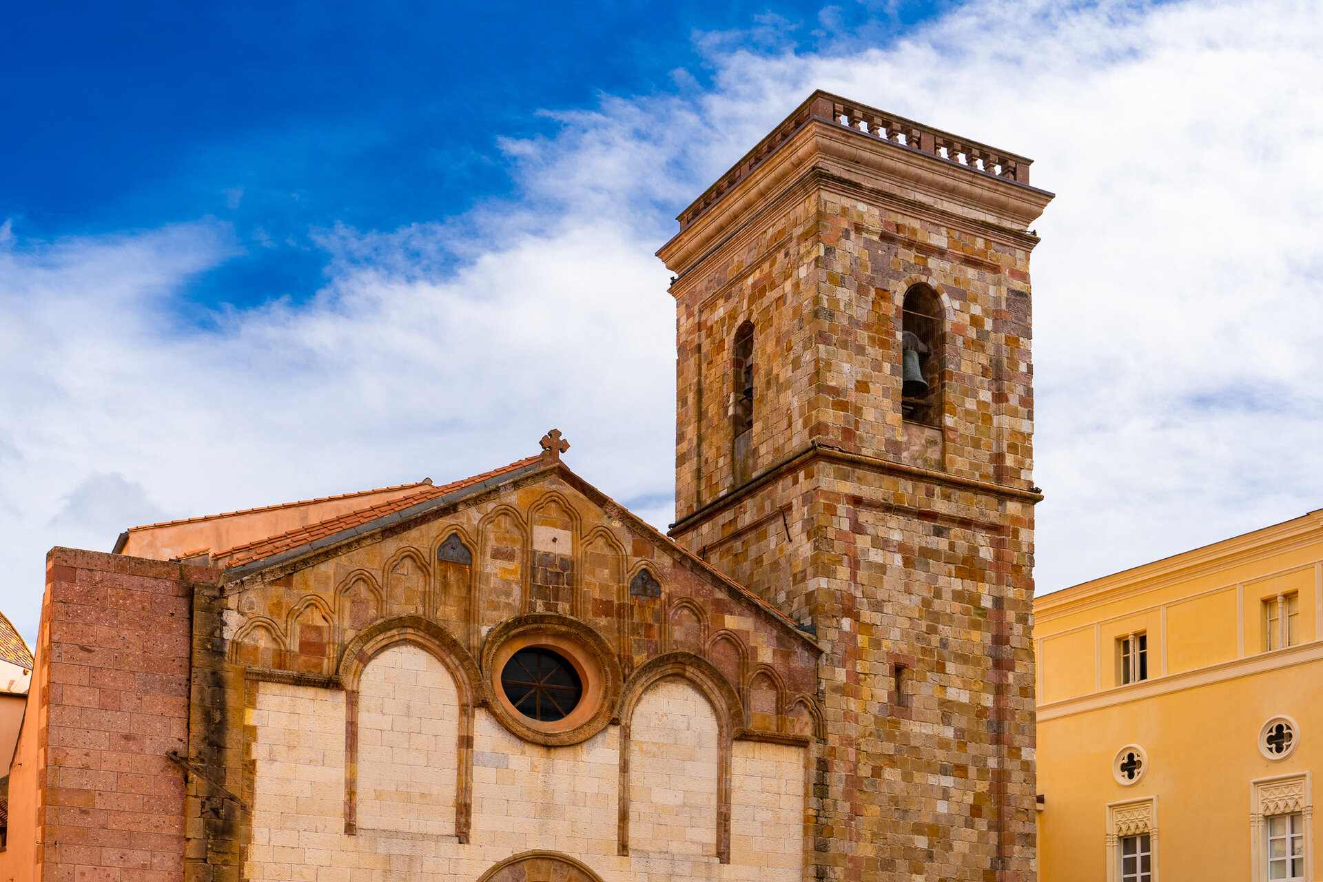 Facciata e campanile di una chiesa storica in pietra sotto cielo azzurro