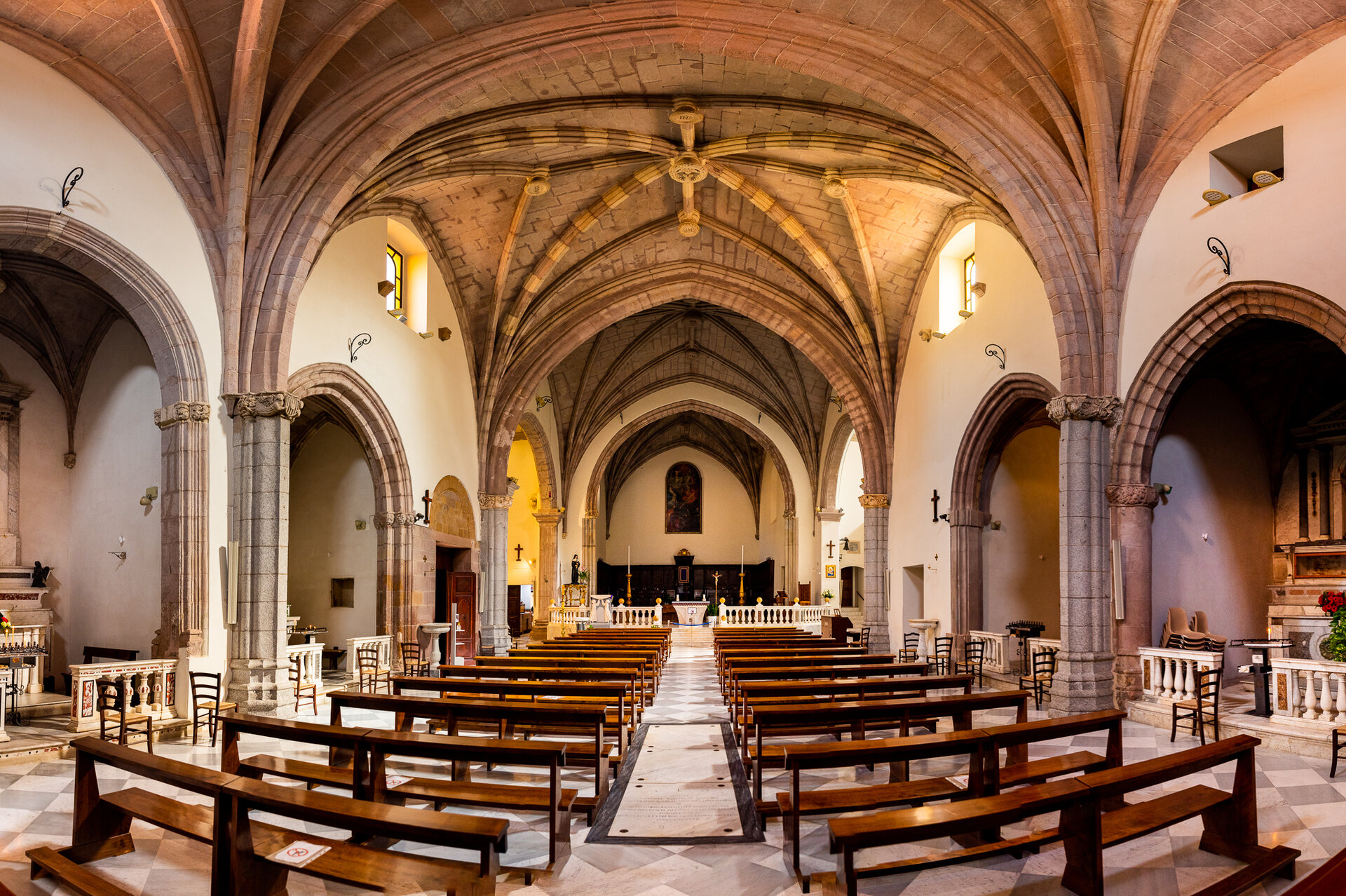 Interno di una chiesa con archi a volta e banchi in legno disposti ordinatamente.