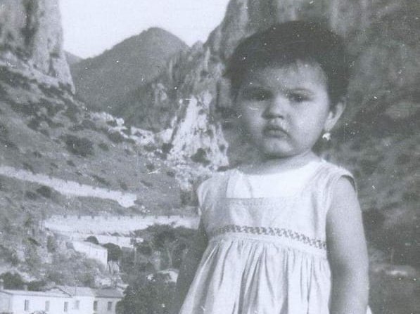 Young girl in light dress standing in rocky mountain landscape in black and white