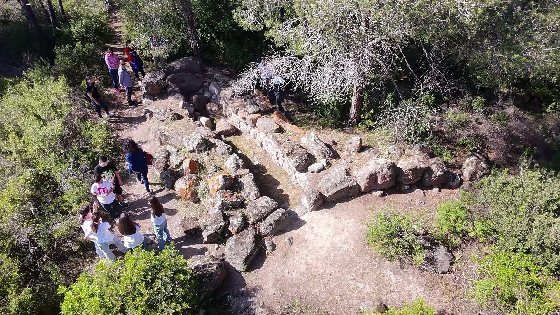 People visiting an archaeological site with ancient stone structures outdoors
