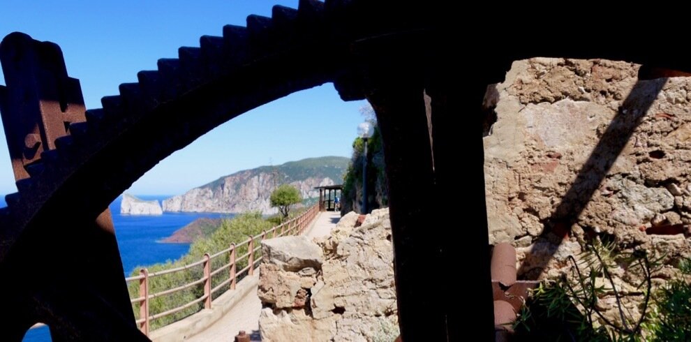 Sea and cliff view through a stone arch with path and railing