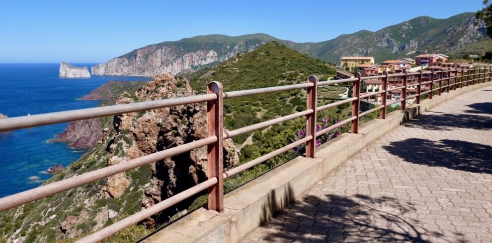 Walkway overlooking cliffs, sea, and mountains in the background.