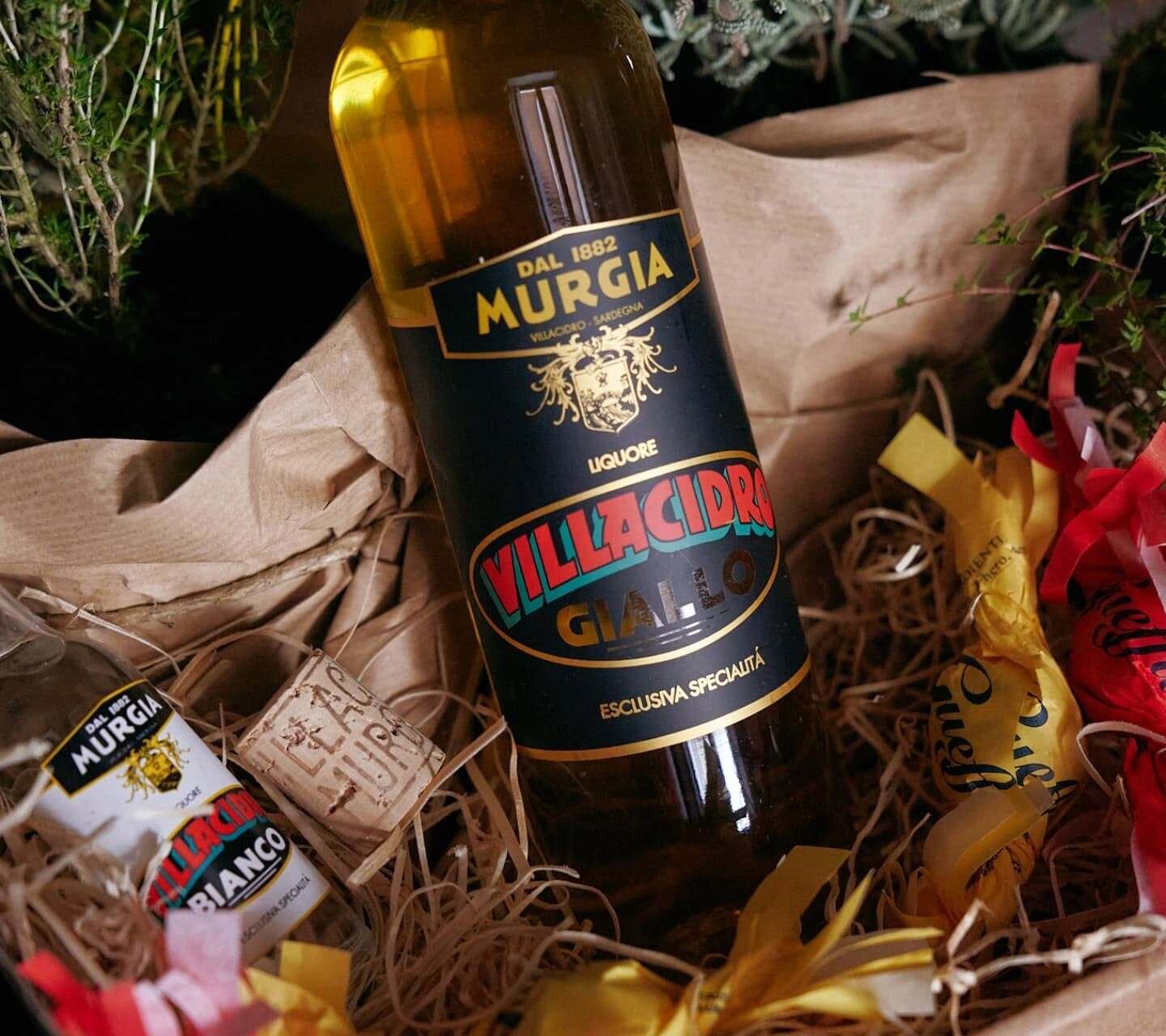 Bottle of Villacidro Giallo Murgia liqueur in gift box with aromatic herbs.