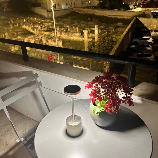 Table ronde avec lampe et pot de fleurs rouges sur balcon la nuit