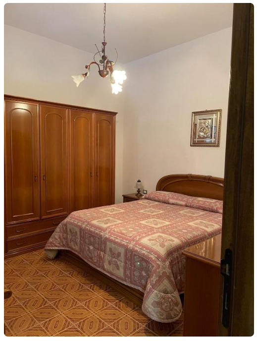 Camera da letto con letto matrimoniale, armadio in legno e lampadario vintage.