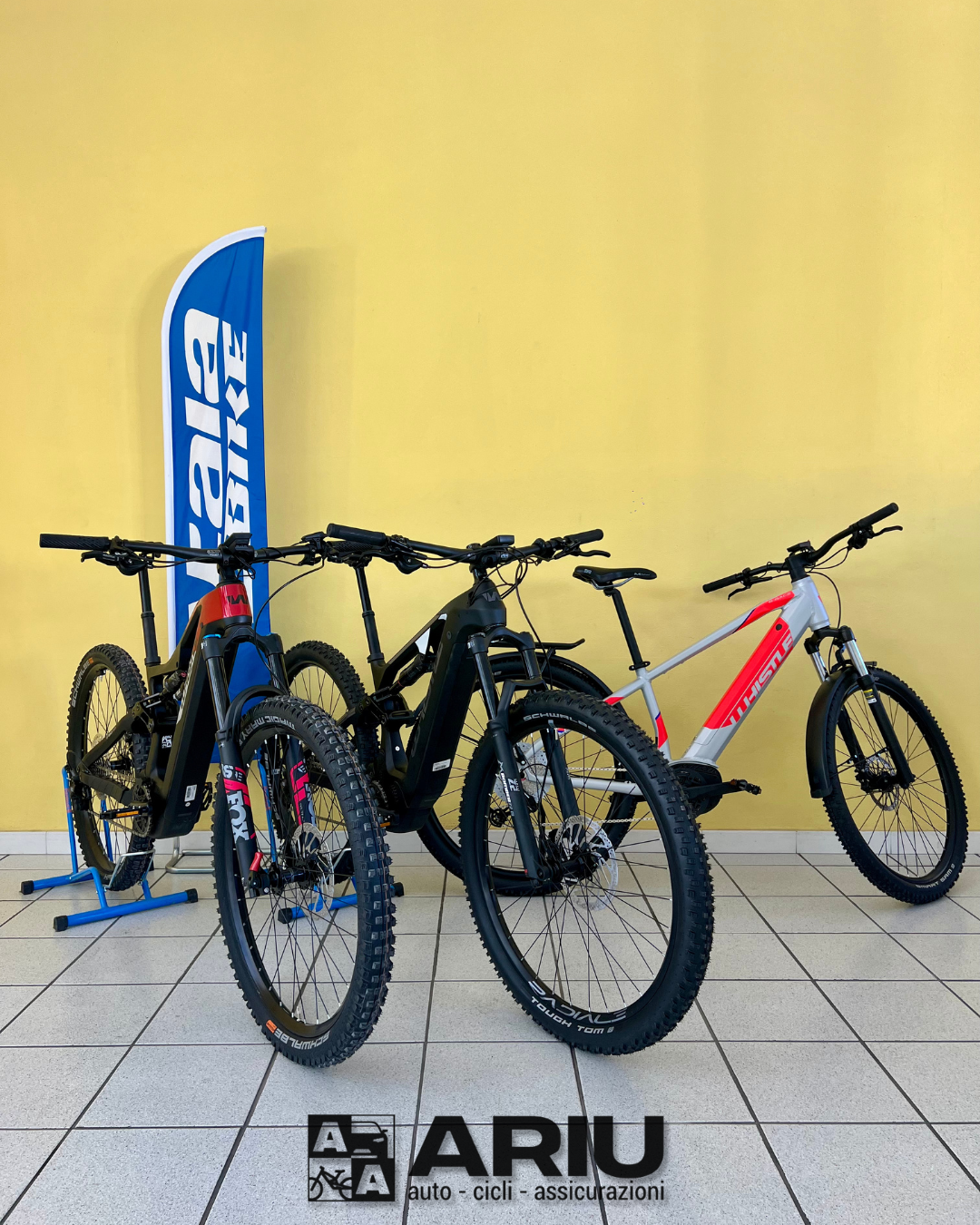 Three electric mountain bikes displayed against a yellow wall