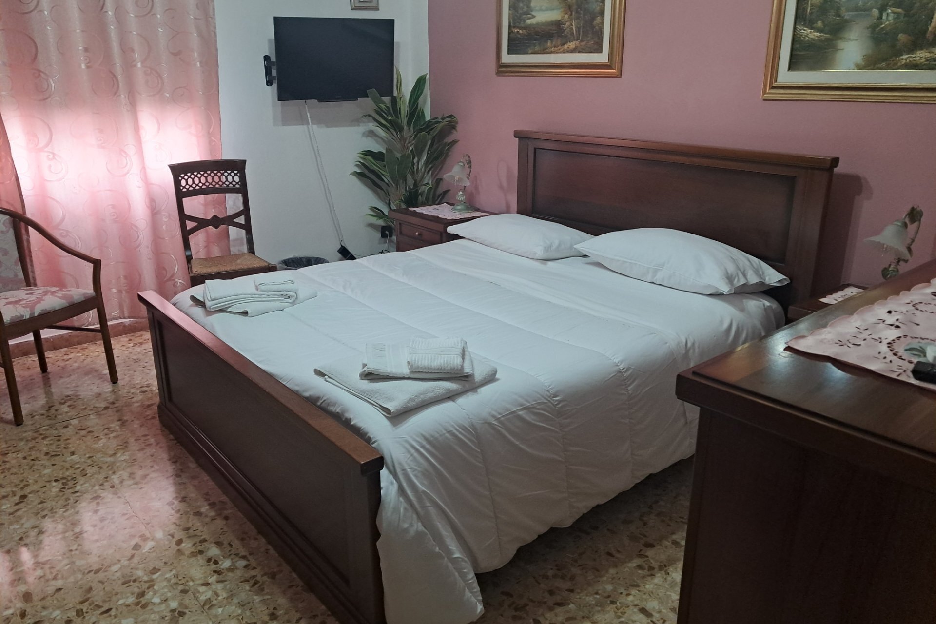 Camera da letto con letto matrimoniale, lenzuola bianche e mobili in legno scuro.