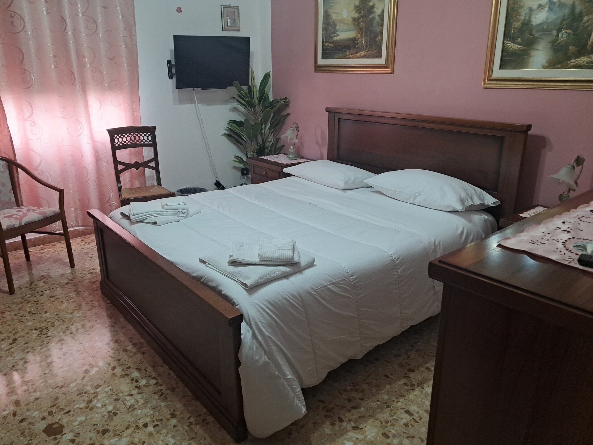 Camera da letto con letto matrimoniale, lenzuola bianche e arredamento classico.