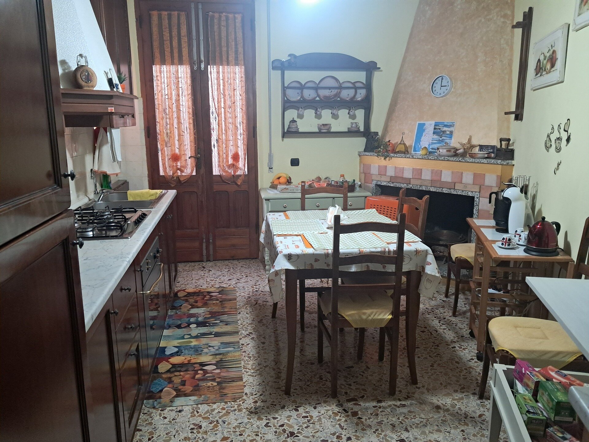 Cucina rustica con tavolo apparecchiato, camino e mobili in legno.