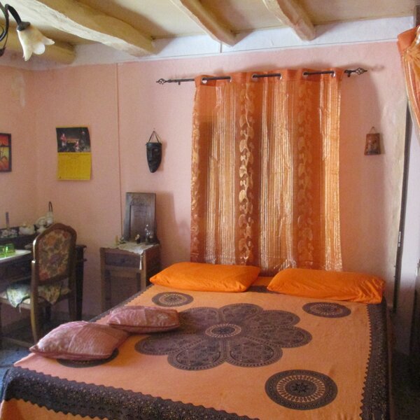 Camera da letto con letto matrimoniale e tende arancioni, arredamento rustico.