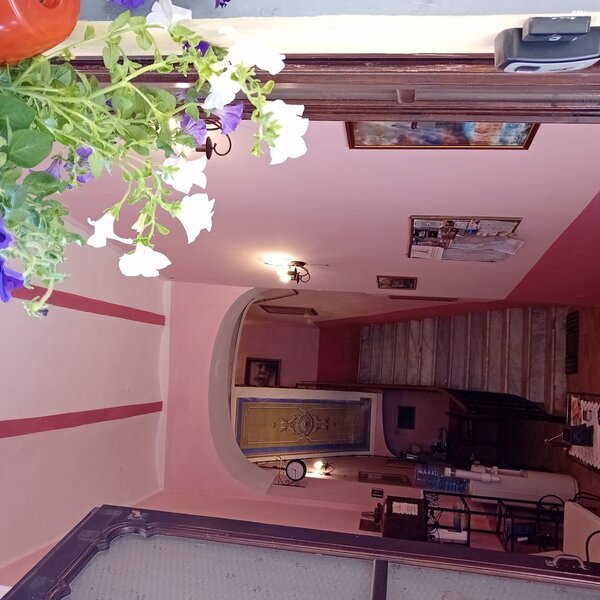 Interno con pareti rosa, scale in marmo e fiori bianchi e viola in primo piano.