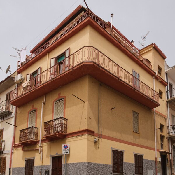 Edificio angolare con balconi in ferro battuto e persiane chiuse