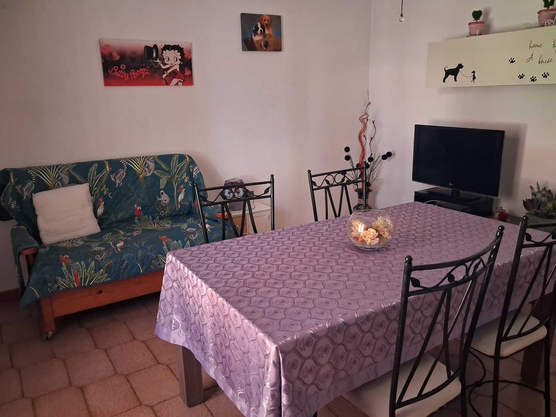 Sala da pranzo con tavolo coperto da tovaglia viola e divano con copertura verde