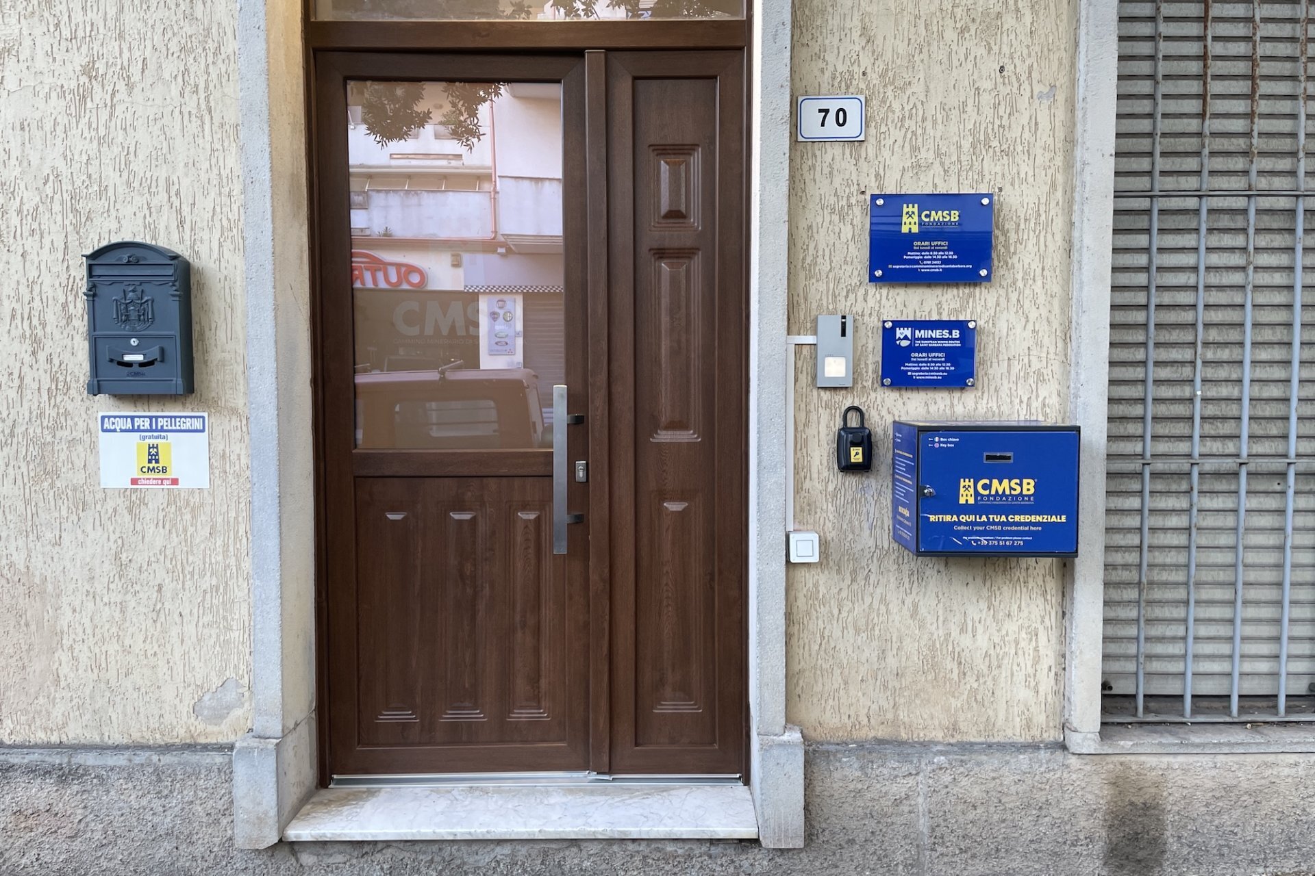 Porta d'ingresso in legno con targhe blu e cassetta per credenziali numero 70