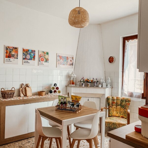 Cucina luminosa con tavolo, sedie bianche e decorazioni floreali.