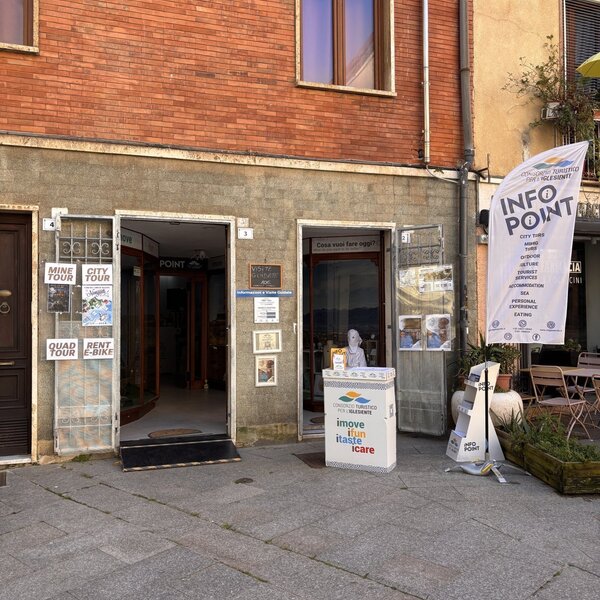 Ufficio informazioni turistiche con cartelli e bandiera all'ingresso di un edificio.