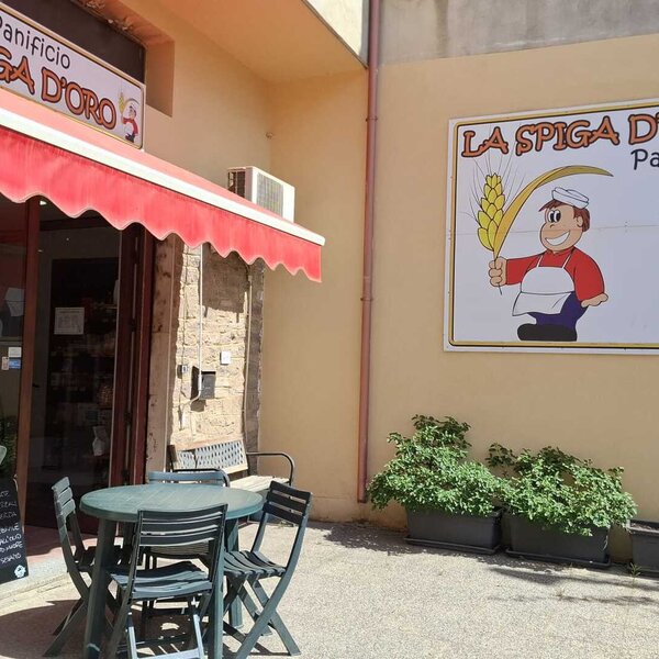 Tavolo e sedie all'esterno di un panificio con insegna colorata