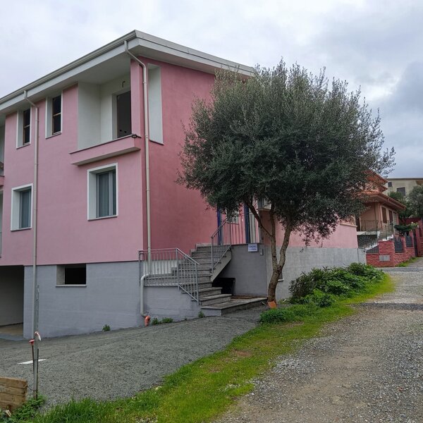 Casa rosa su due piani con albero e vialetto di ghiaia davanti