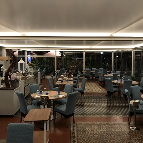 Interno di un ristorante elegante con tavoli apparecchiati e sedie blu.