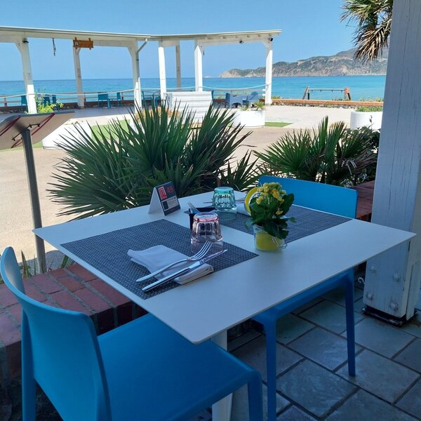 Tavolo apparecchiato con vista sul mare e vegetazione mediterranea