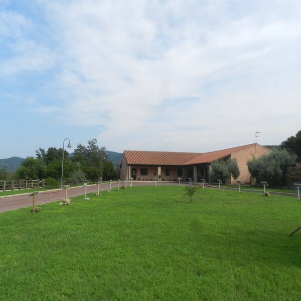 Rural house with tiled roof and green lawn under cloudy sky